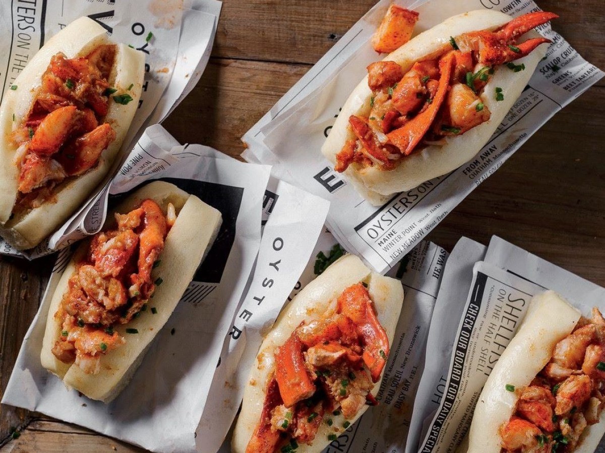 a couple of hot dogs with different toppings sitting on a wooden table