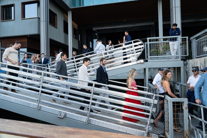 People in formal wear walking down a ramp at a modern building exterior.