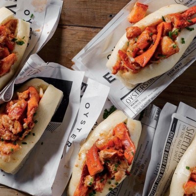 a couple of hot dogs with different toppings sitting on a wooden table