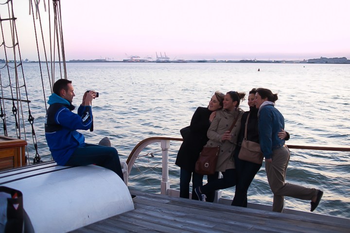 a group of people sitting on a bench next to a body of water