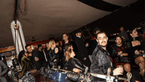 People in semi-formal attire socializing on a boat at night.