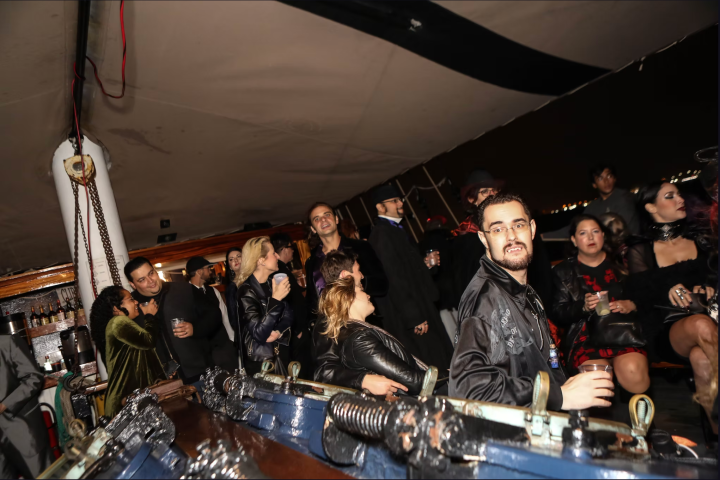 People in semi-formal attire socializing on a boat at night.