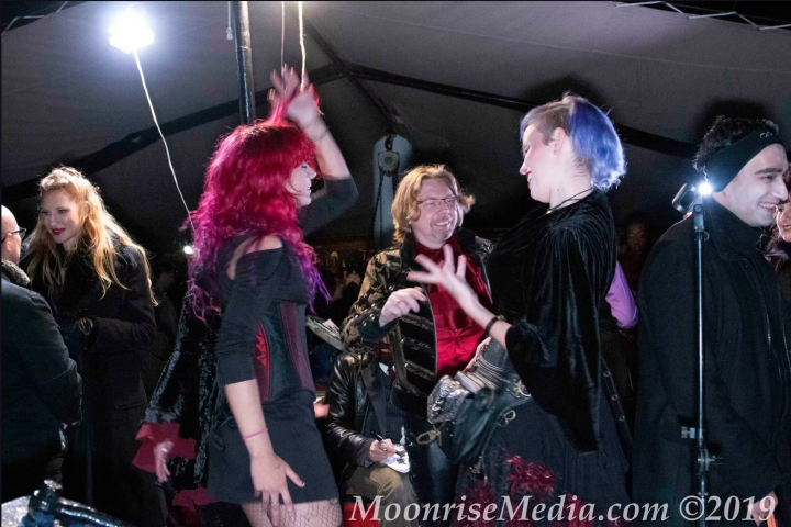 People in colorful outfits dancing and chatting at a lively indoor event.